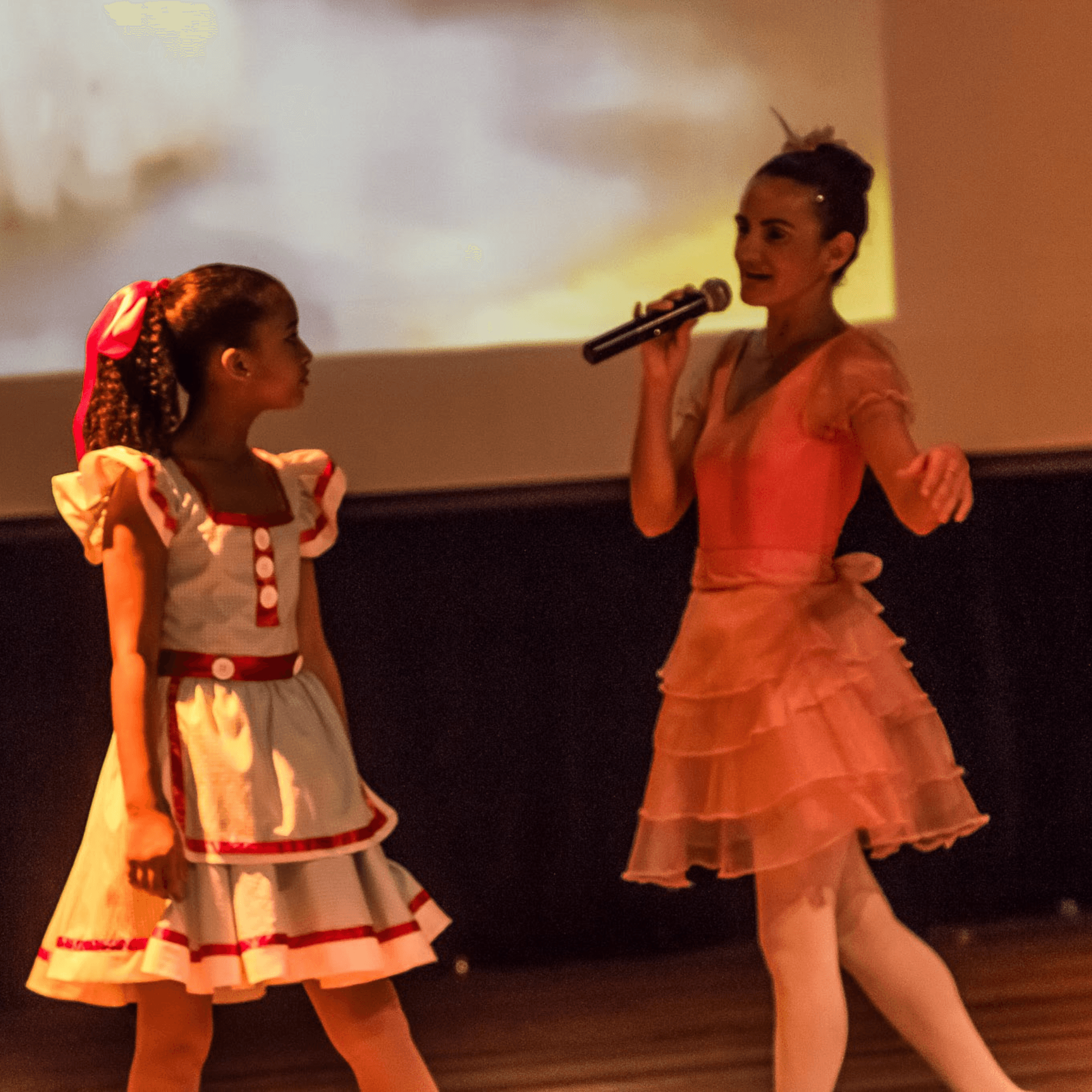 Nellva cantando em cena ao lado de uma bailarina em A Dança de OZ