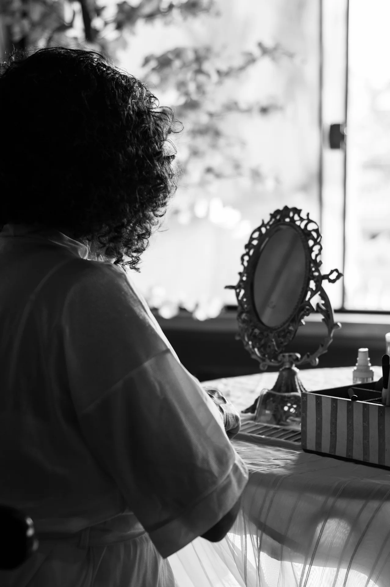 Nellva diante de um espelho de mesa, em fotografia em preto e branco