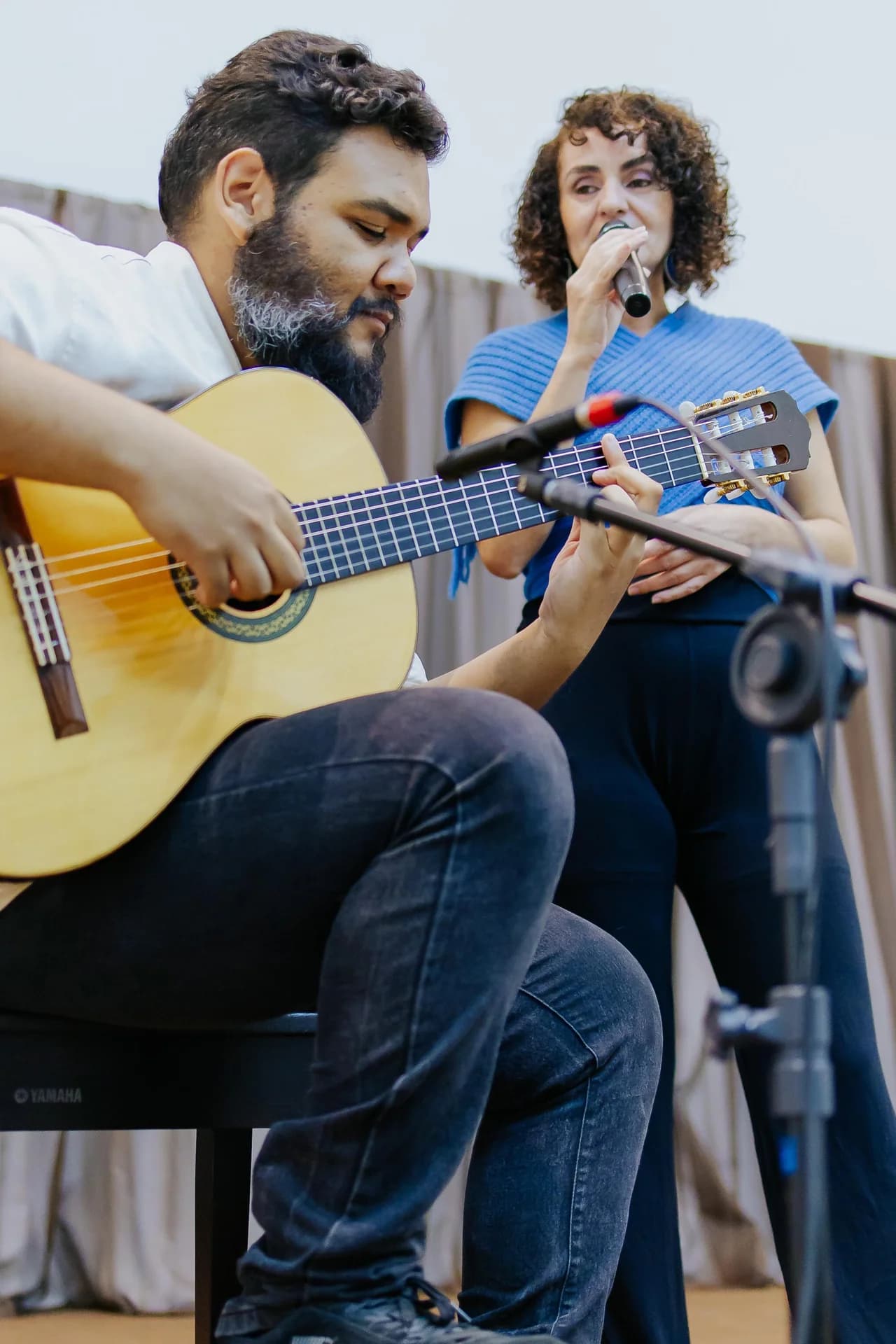 Nellva ao microfone, com um violonista em primeiro plano
