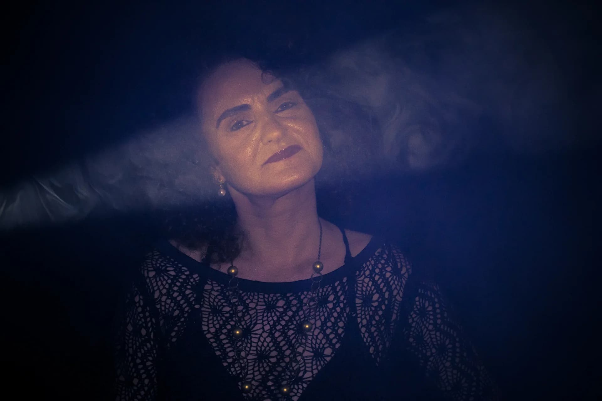 Retrato de Nellva com blusa de renda preta sob uma faixa de luz azul